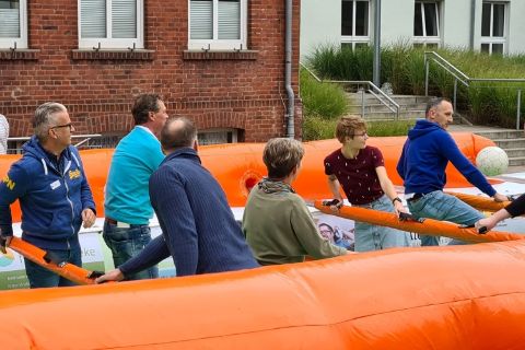 WiR Mitarbeitende spielen Menschen-Kicker