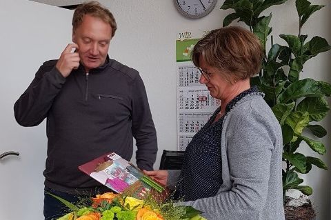 Frank Ribbers überreicht Anne Bröker einen Blumenstrauß und ein Geschenk zum 10-jährigen Dienstjubiläum bei der WiR Solutions