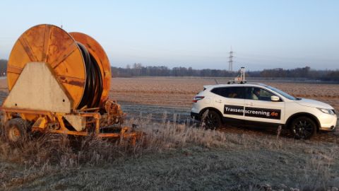 Trassenscreening-Auto auf einem Feld neben Kabeltrommel
