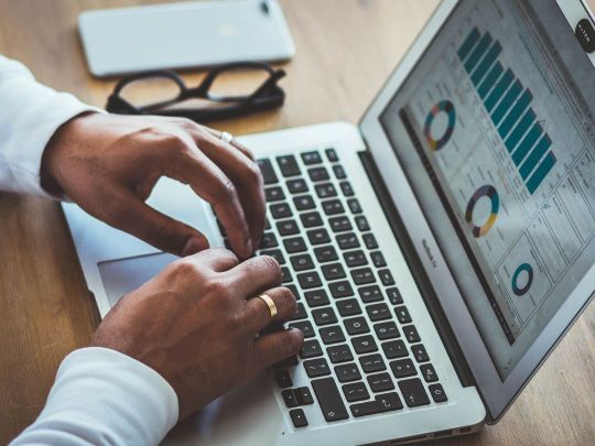 Person vor Laptop mit verschiedenen Statistiken