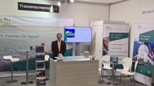 Zwei Männer stehen mit einem Papierplan vor Strommästen