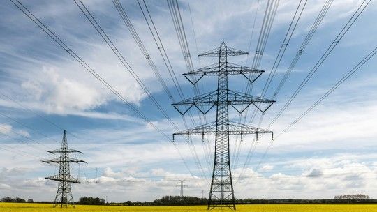 Strommasten in einem Rapsfeld