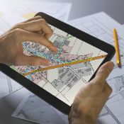 Tablet, auf dem eine Hand an ein Beispielbild zur Netzplanung mit verschiedenen Straßenzügen zu sehen ist